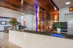 A hotel reception area with a marble counter, wooden ceiling, and a clock.