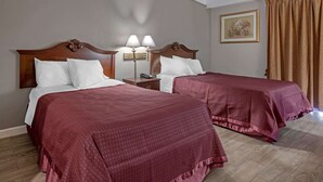 Two double beds with matching headboards and footboards, a nightstand with a lamp, and a framed picture on the wall. - Rodeway Inn Clermont North (Clermont)