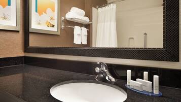 A bathroom with a large mirror, a sink, and a towel rack.
