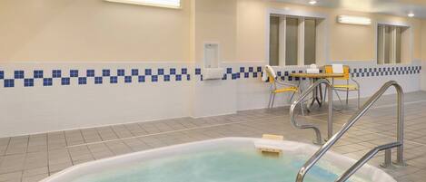 A pool area with a hot tub, a table with chairs, and a window.