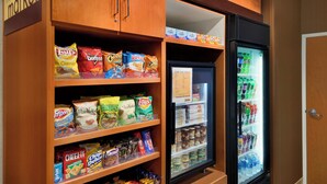 Zona de venta automática con aperitivos y bebidas, que ofrece diversas opciones de bocadillos y un dispensador refrigerado.