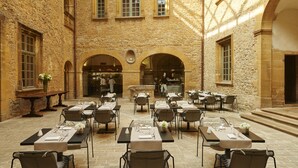 Un comedor al aire libre con paredes de piedra y mesas dispuestas para una comida.