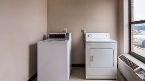 A laundry room with two white washers and dryers, a window, and a vent. - Econo Lodge Andrews Air Force Base (Clinton)