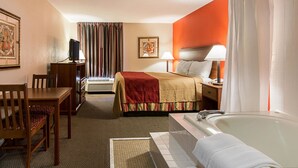 A hotel room with a bed, a desk with a chair, a television, a bathroom with a bathtub, and a shower curtain. - Econo Lodge Andrews Air Force Base (Clinton)