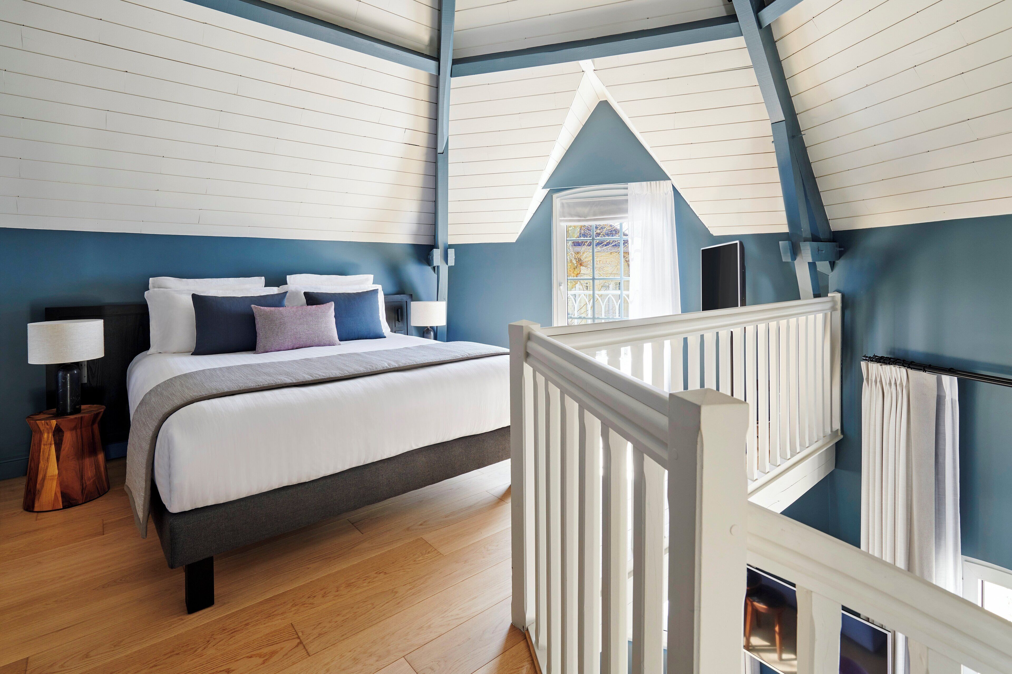 A bedroom with a bed, bedside tables, a window, and a view of the outside.