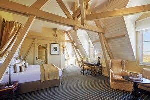 Una habitación con cama, una silla, una mesa y un ventanal.