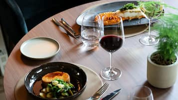 A dining table with plates of food, wine glasses, and cutlery.