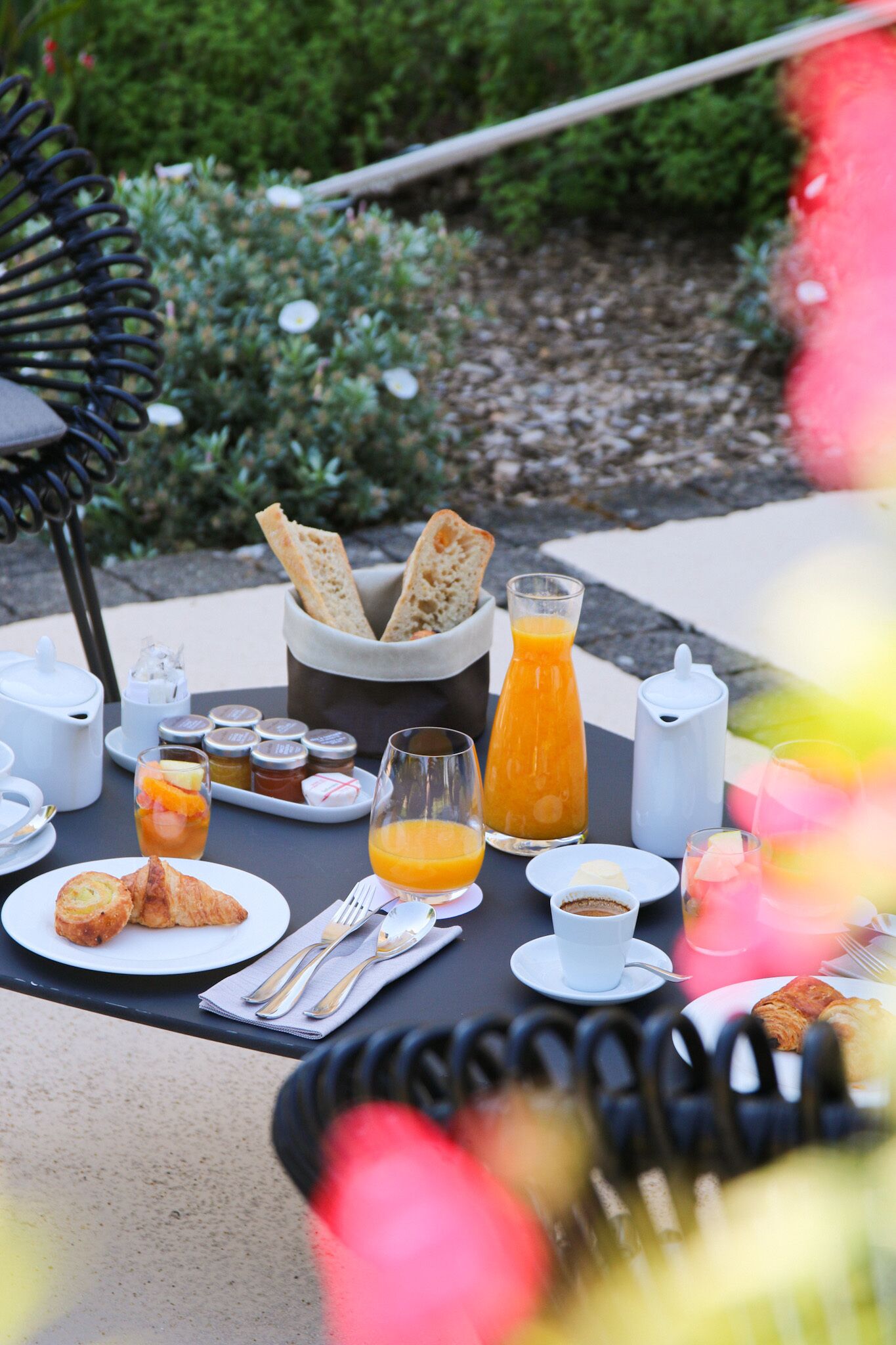 Un petit-déjeuner en plein air avec des croissants, du pain, du jus de fruits et du café.