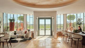 A spacious living area with a large window, a sofa, chairs, a coffee table, and a dining area with a table and chairs.