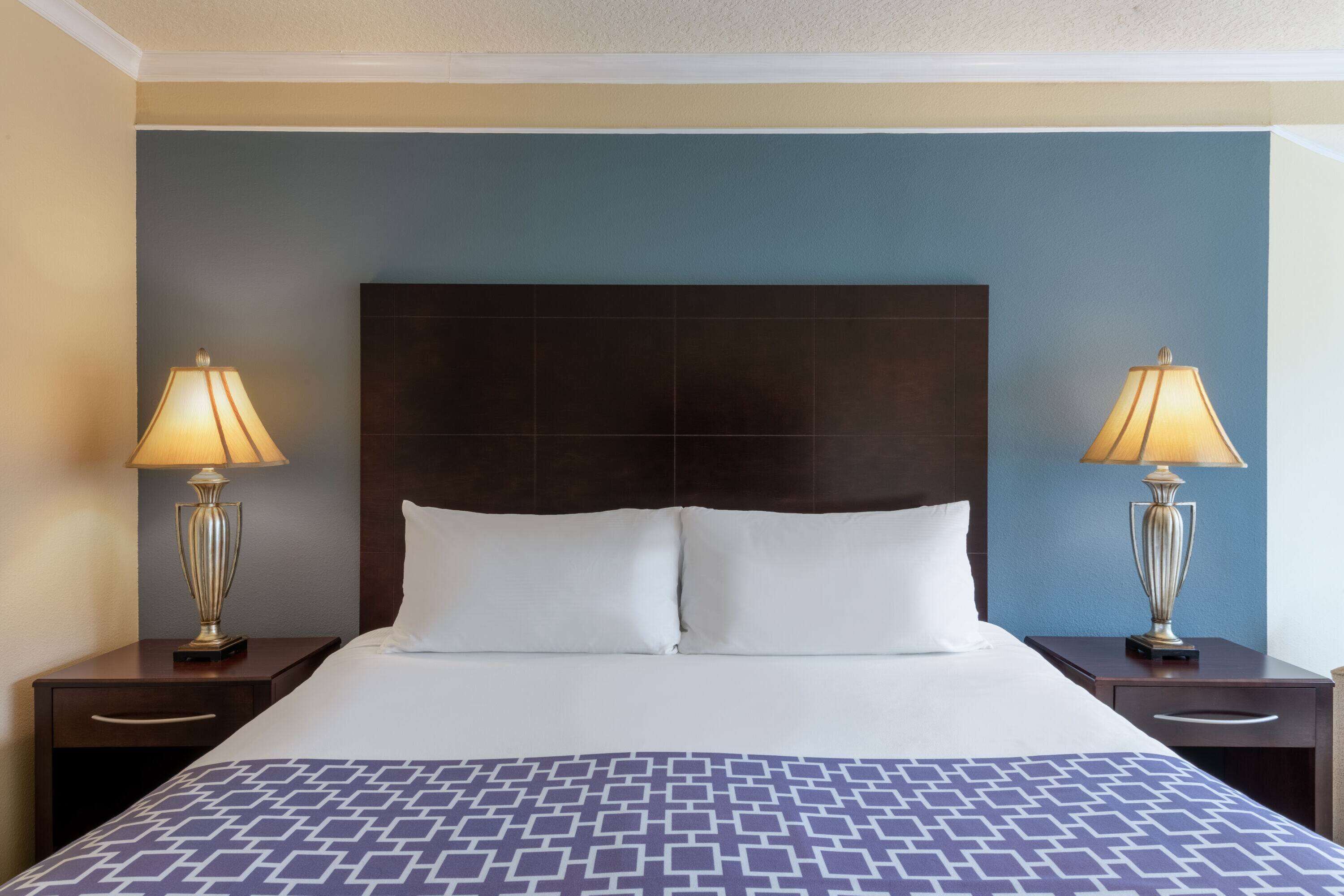 Una habitación de hotel con una cama grande, dos mesitas de noche y lámparas.