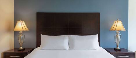 Una habitación de hotel con una cama grande, dos mesitas de noche y lámparas.
