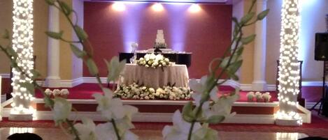 A stage with a table and floral arrangements, surrounded by columns with lights.