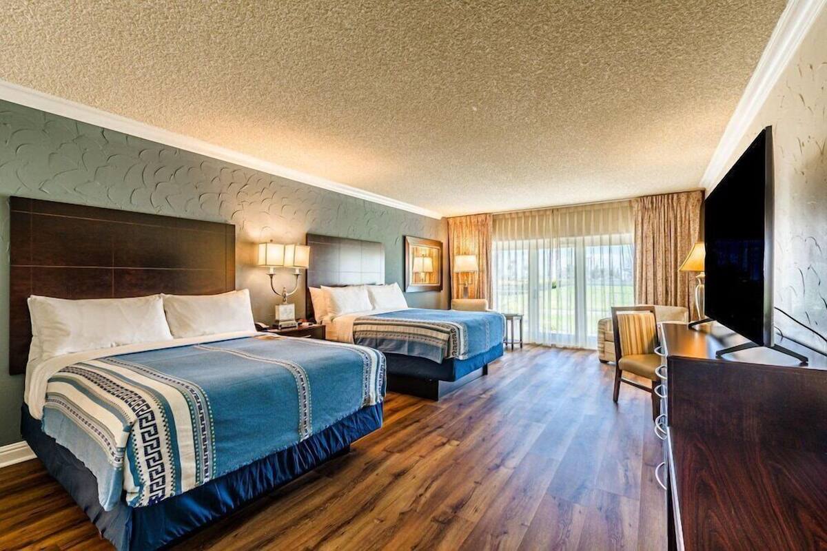 A hotel room with two beds, a TV, a desk, and a chair.