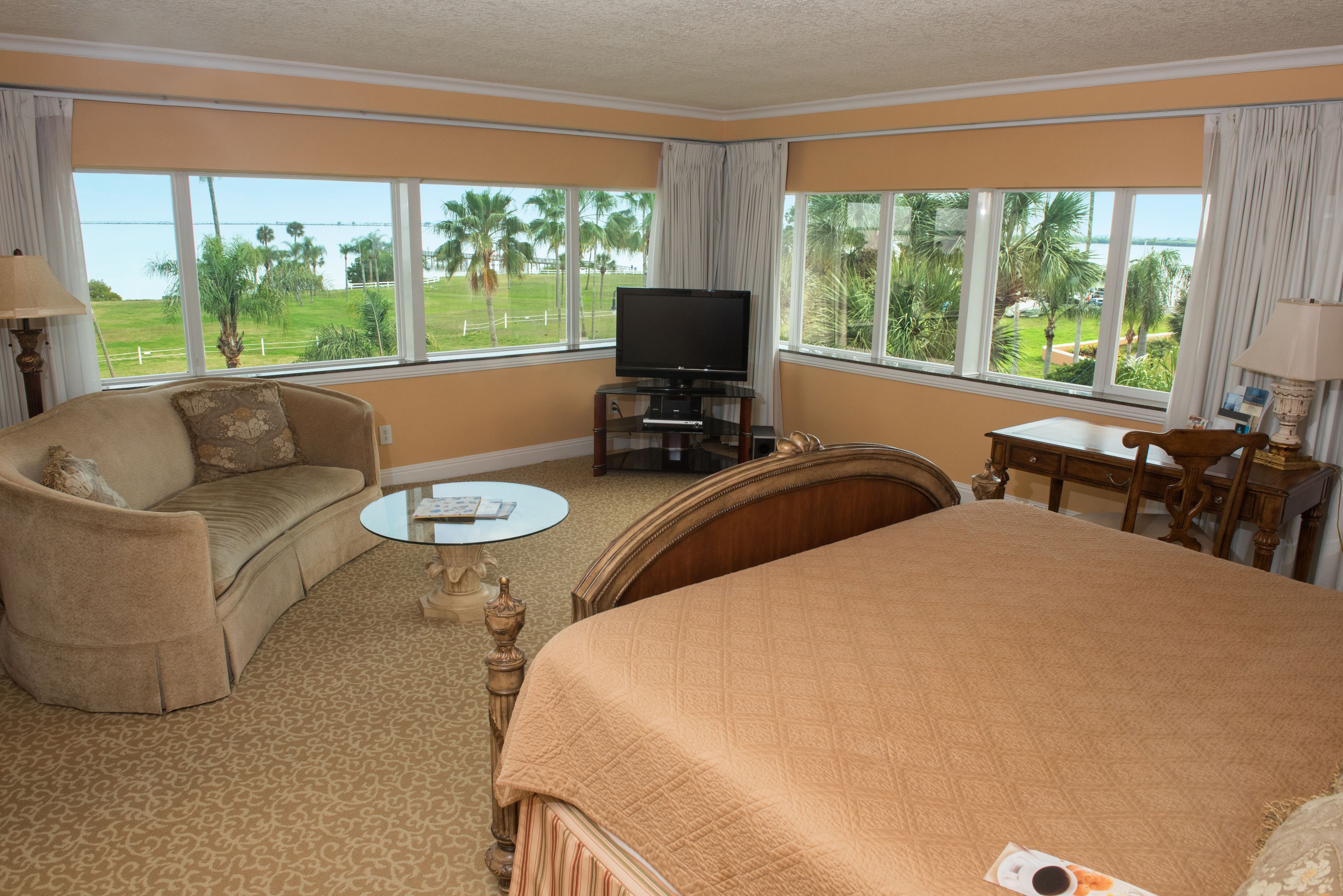 Habitación de hotel con una cama grande, un sofá, un televisor y vistas al exterior.