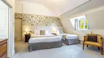 A bedroom with two beds, a wooden chair, a window with a view, and a chandelier.