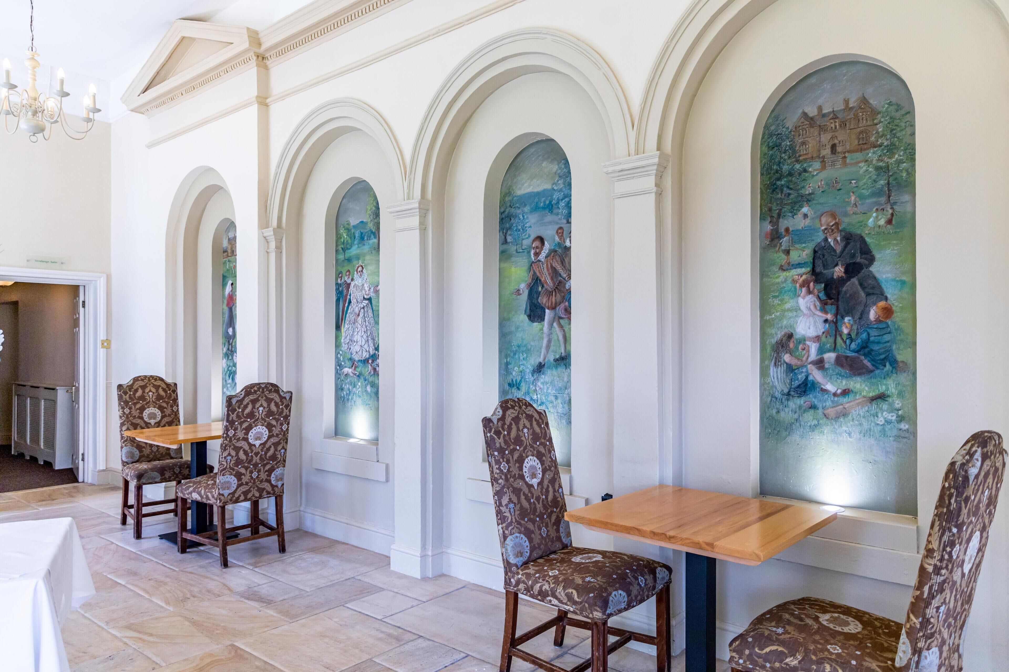Un espace repas avec une table en bois et des chaises à motifs, des plafonds en arc de cercle et une fresque murale.