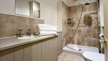A bathroom with a bathtub, a shower, and a sink with a mirror above it.