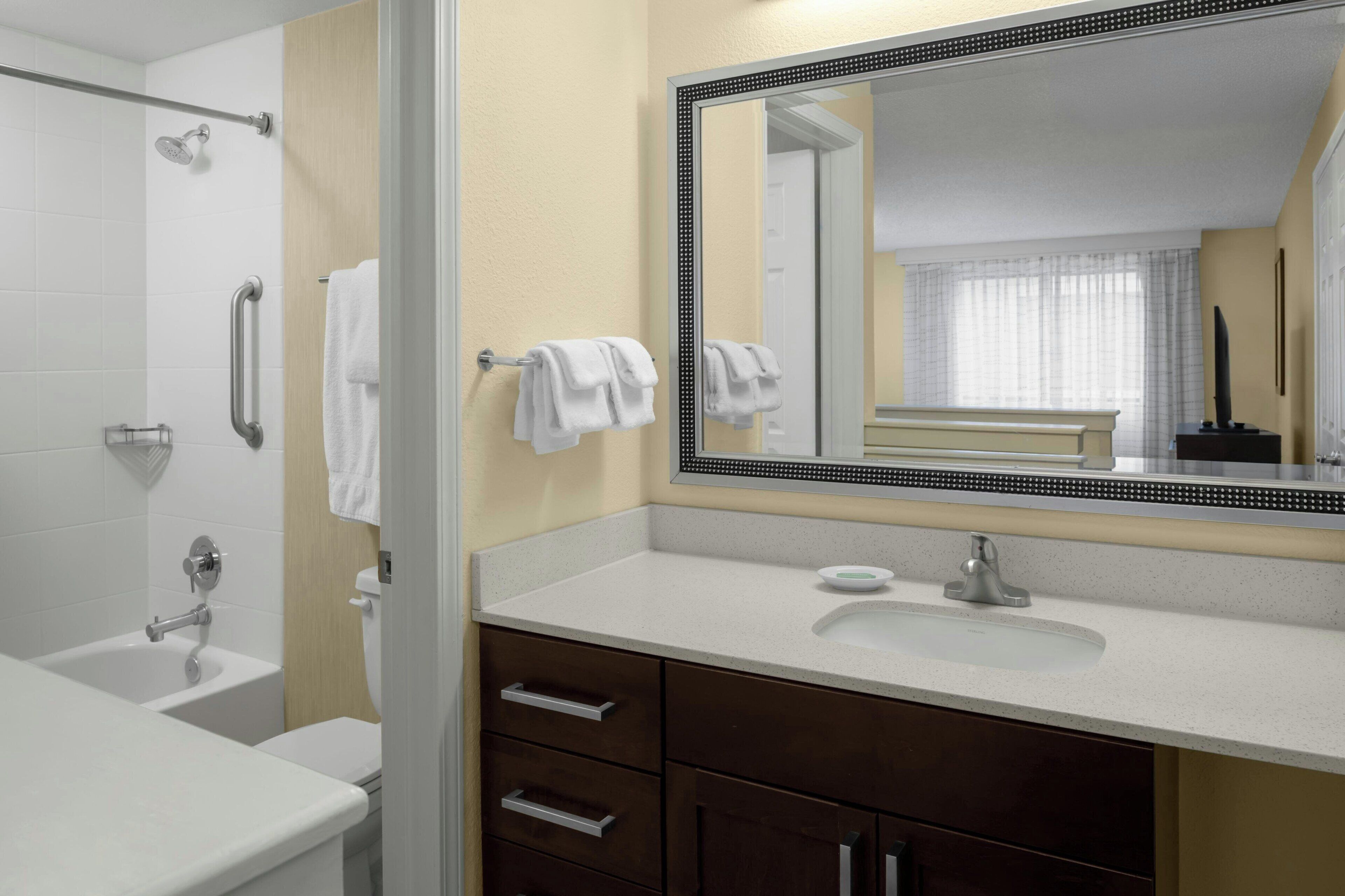 A modern bathroom with a bathtub, a sink, and a large mirror.