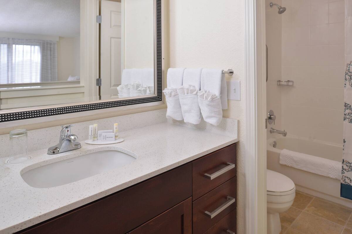 A bathroom with a sink, mirror, and a shower area.