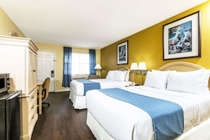 Una habitación de hotel con dos camas, un escritorio, un aparador y un microondas.