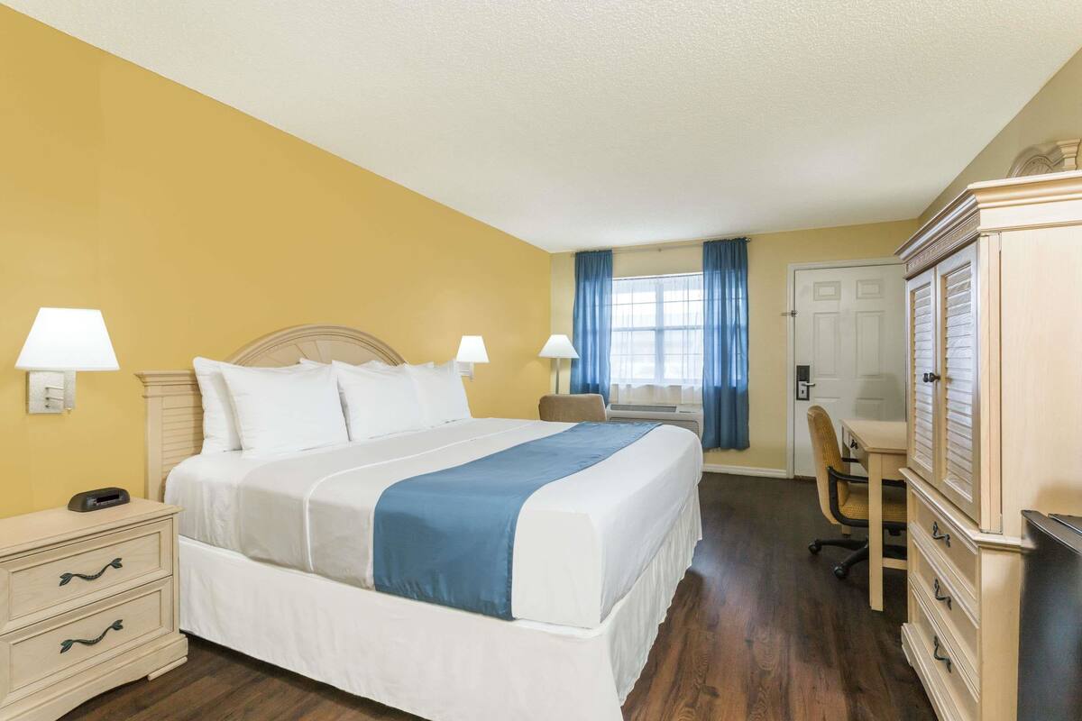 A hotel room with a bed, bedside tables, a desk, and a wardrobe.