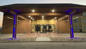 A building with a covered entrance, a tiled roof, and a paved walkway leading to the entrance. - Travelodge by Wyndham Odessa (Odessa)