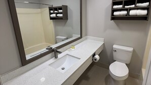 A modern bathroom with a large mirror, a sink, a toilet, and a towel rack. - Travelodge by Wyndham Odessa (Odessa)