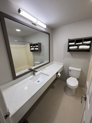 Een moderne badkamer met een grote spiegel, een wastafel, een toilet en een handdoekhouder.