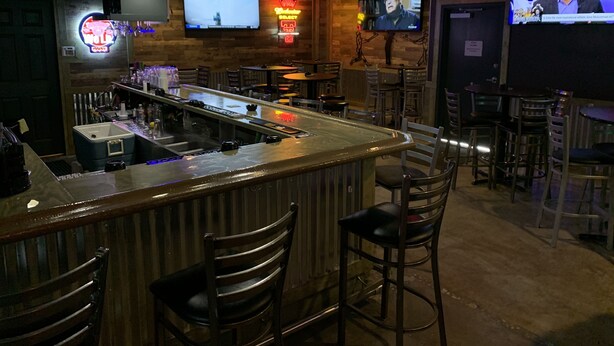 A bar area with a counter, stools, and televisions displaying sports. - Travelodge by Wyndham Odessa (Odessa)