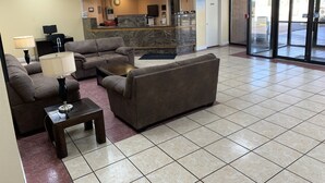 A lobby with a reception desk, a sofa, a coffee table, and a lamp. - Travelodge by Wyndham Odessa (Odessa)