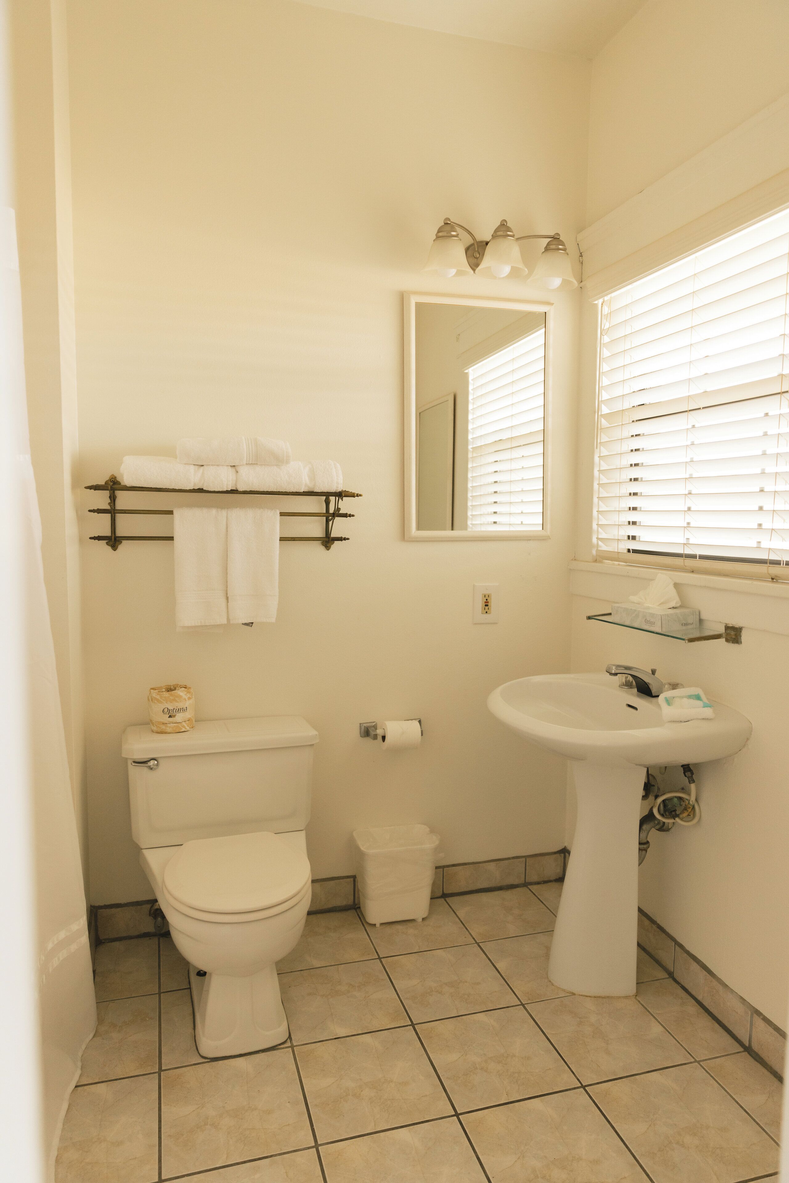 A bathroom with a toilet, sink, and a towel rack with folded towels.