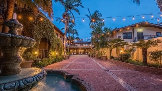 A courtyard with a fountain, palm trees, and string lights. - Historic Santa Maria Inn (Santa Maria)