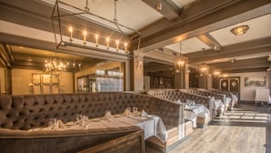 A restaurant with a long, curved seating area featuring cushioned booths and tables set for dining. - Historic Santa Maria Inn (Santa Maria)