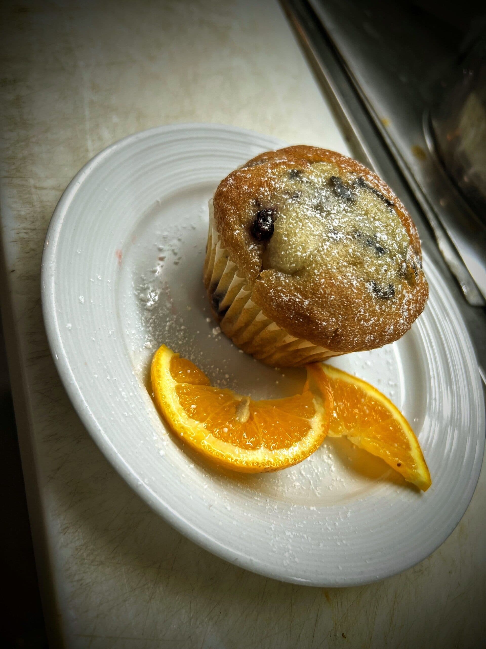 Un muffin sobre un plato con una rodaja de naranja.