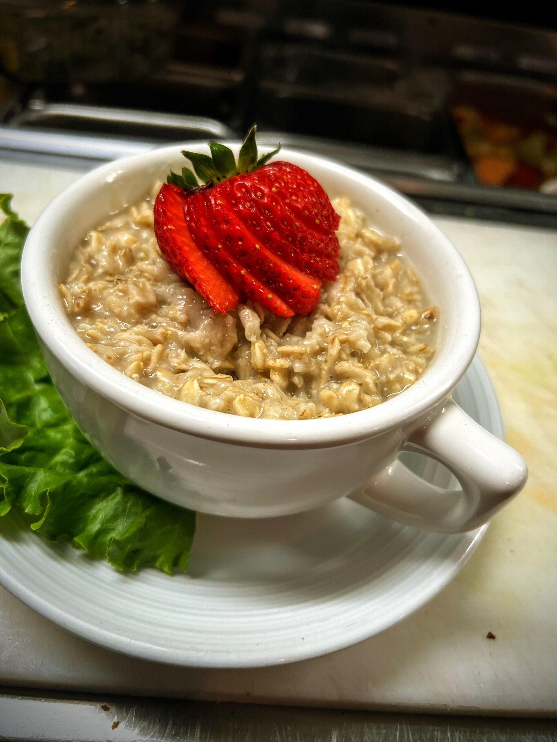 A bowl of oatmeal with strawberries on a white plate.