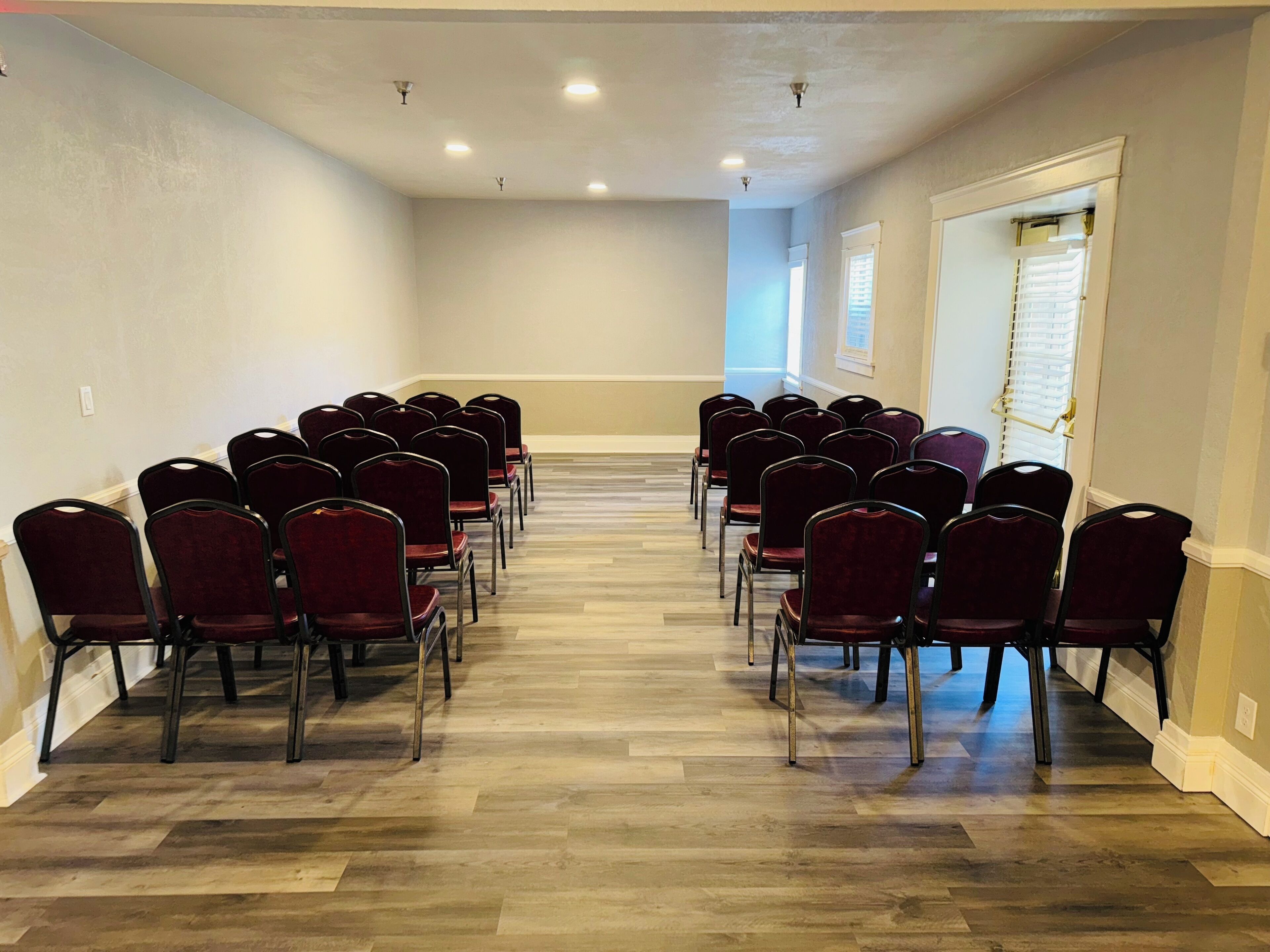 Une salle de conférence avec des rangées de chaises et un plancher en bois.
