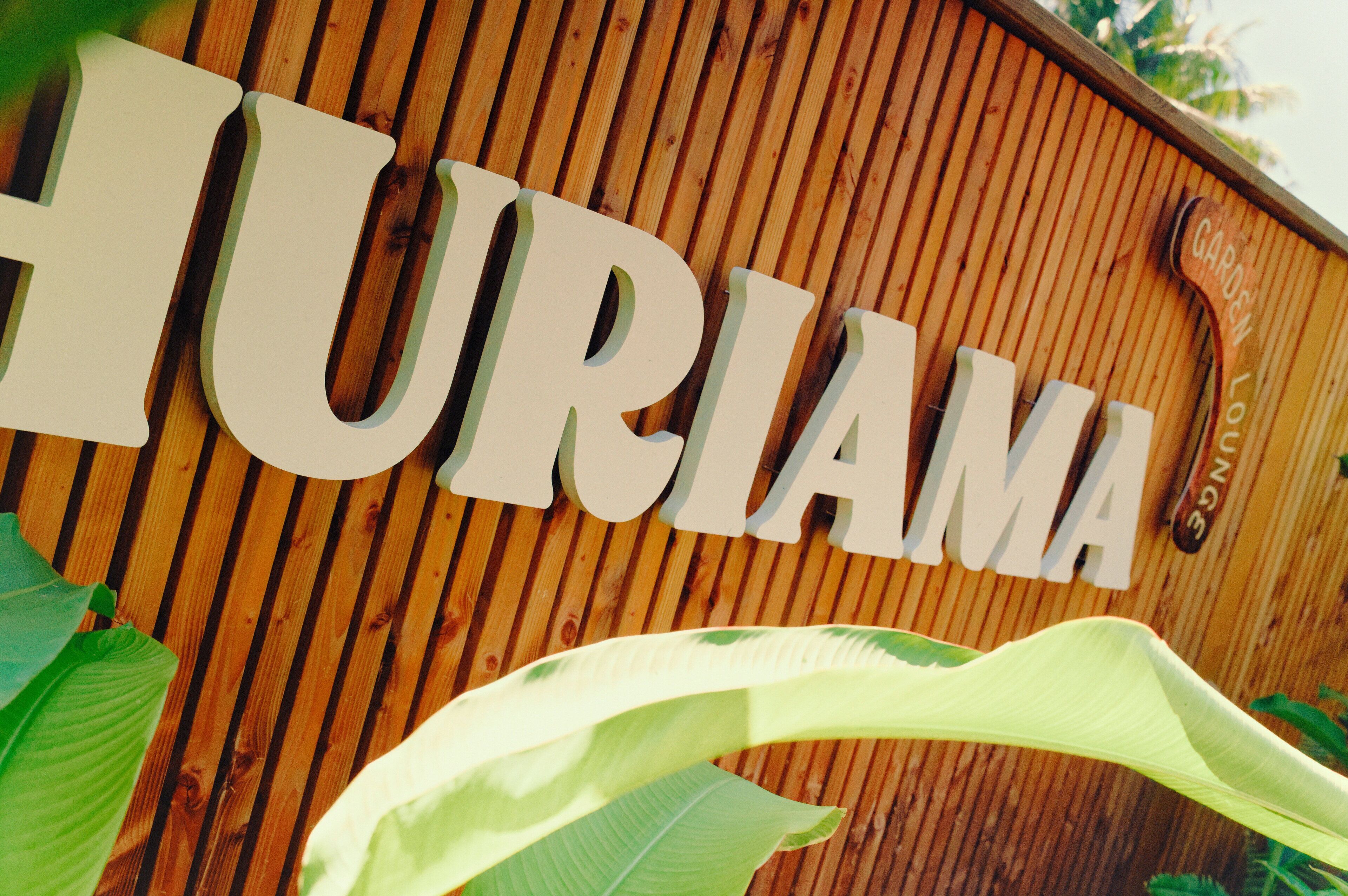 Una pared de madera con el nombre "HURIAMA" en letras grandes.