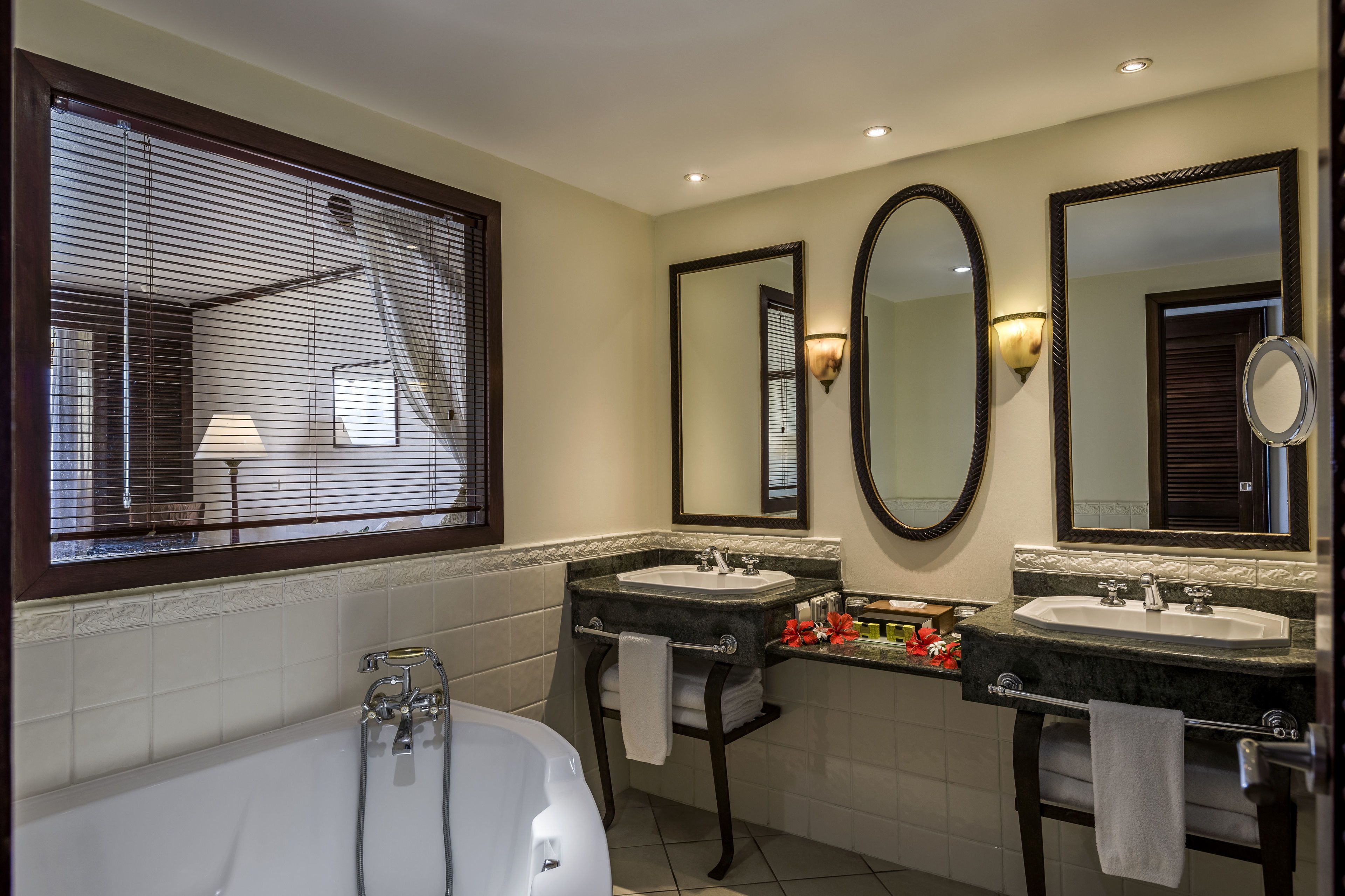 A bathroom with a bathtub, two sinks, and three mirrors.