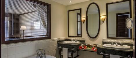 A bathroom with a bathtub, two sinks, and three mirrors.