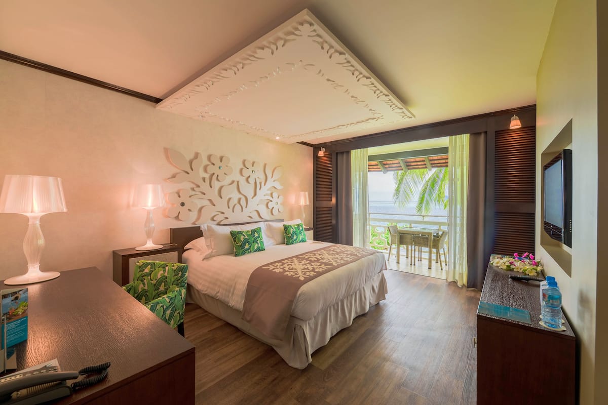 A hotel room with a large bed, bedside lamps, a desk with a water bottle, and a TV on the wall.