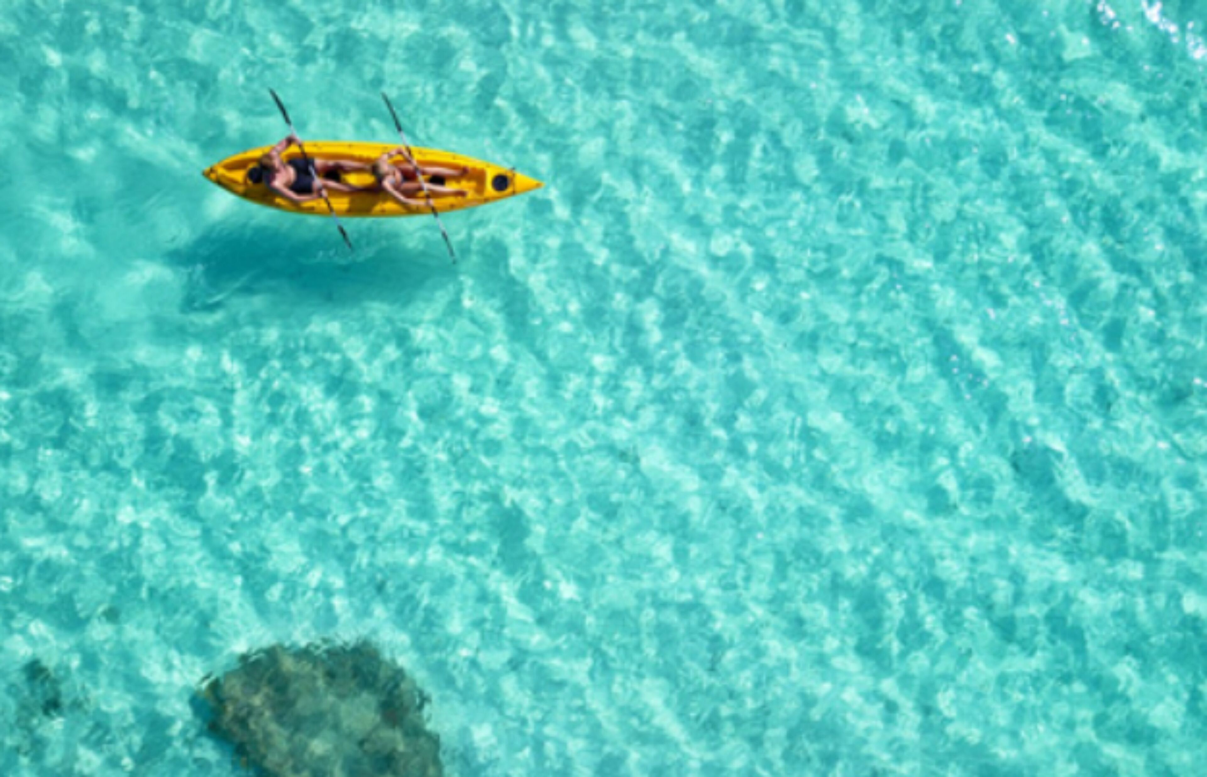 A yellow kayak on clear turquoise water.