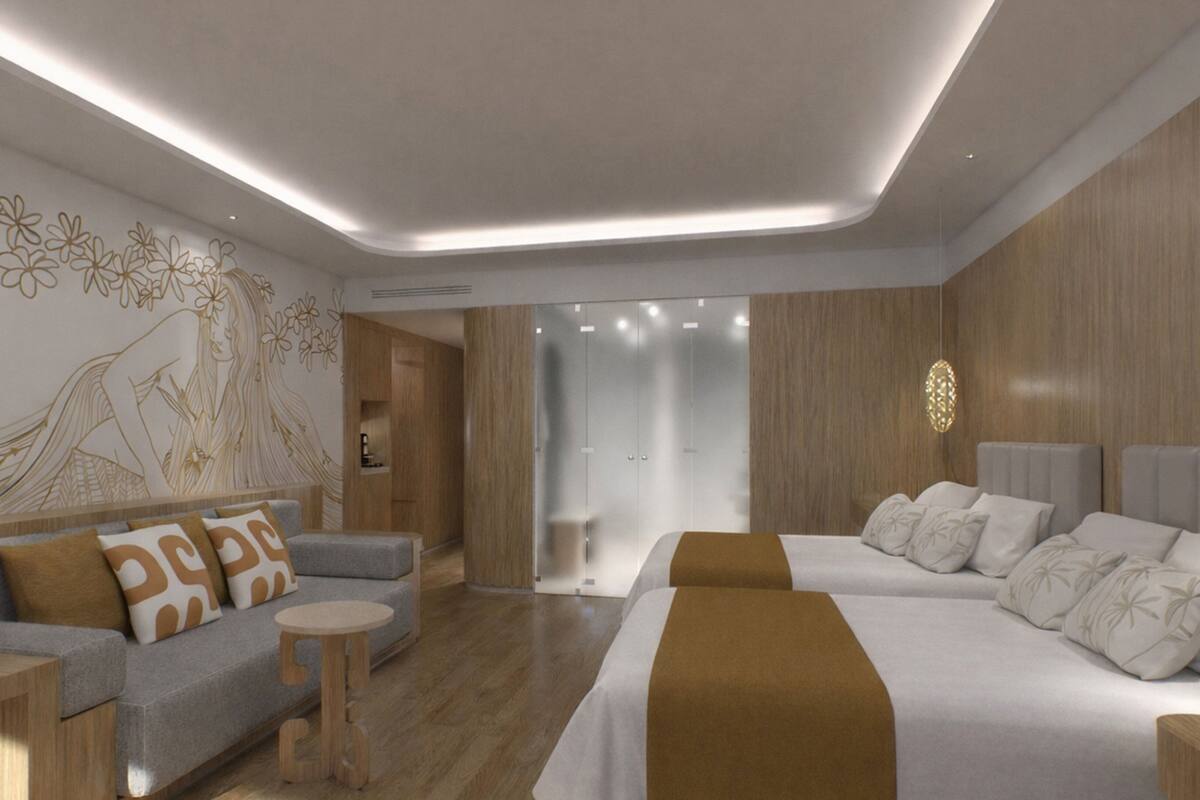 A modern hotel room with a sofa, a bed, a round table, and a decorative wall mural.
