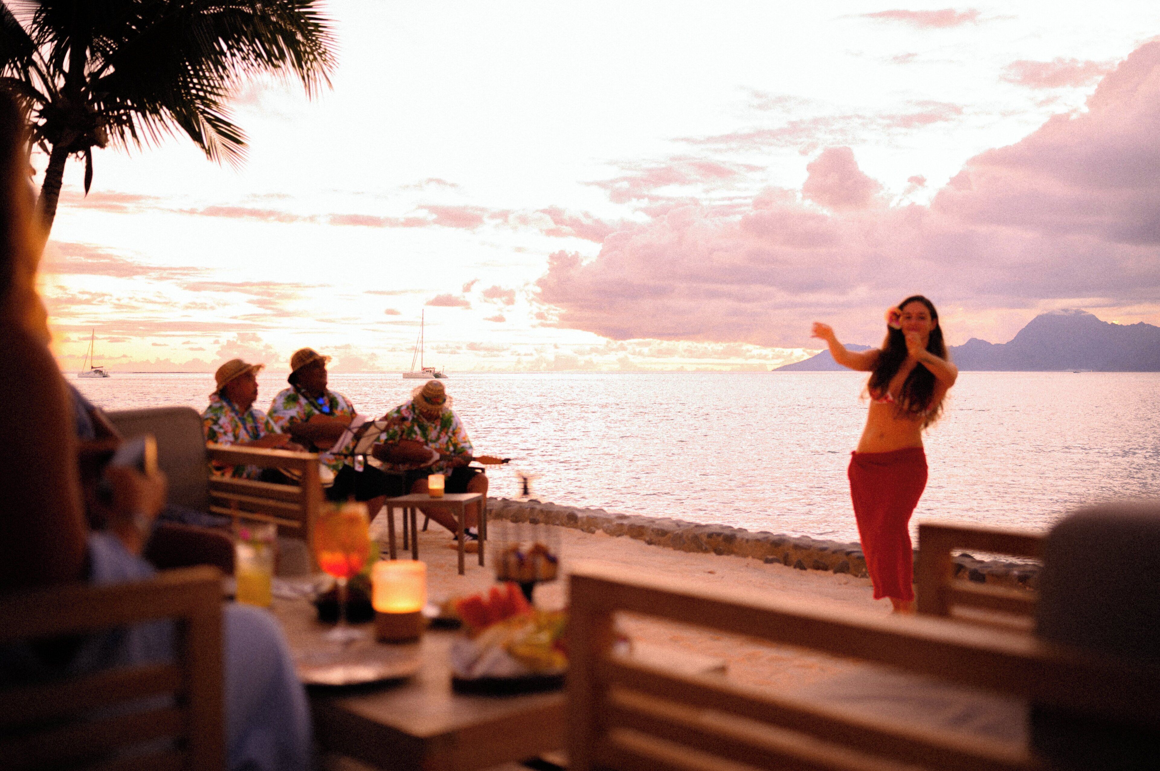 A sunset view with a dining area overlooking the water, featuring tables and chairs.