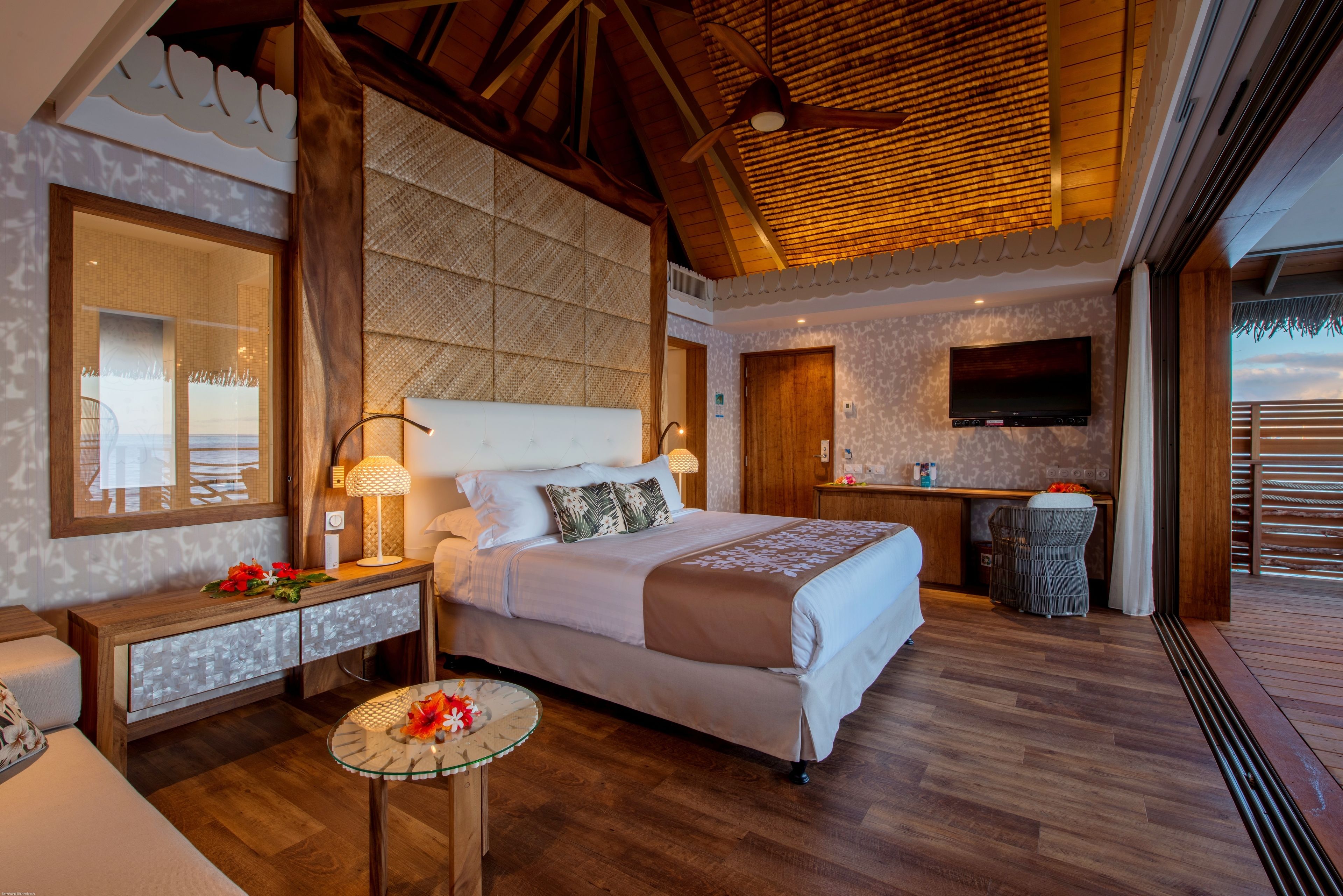 A spacious bedroom with a large bed, a desk, and a TV.