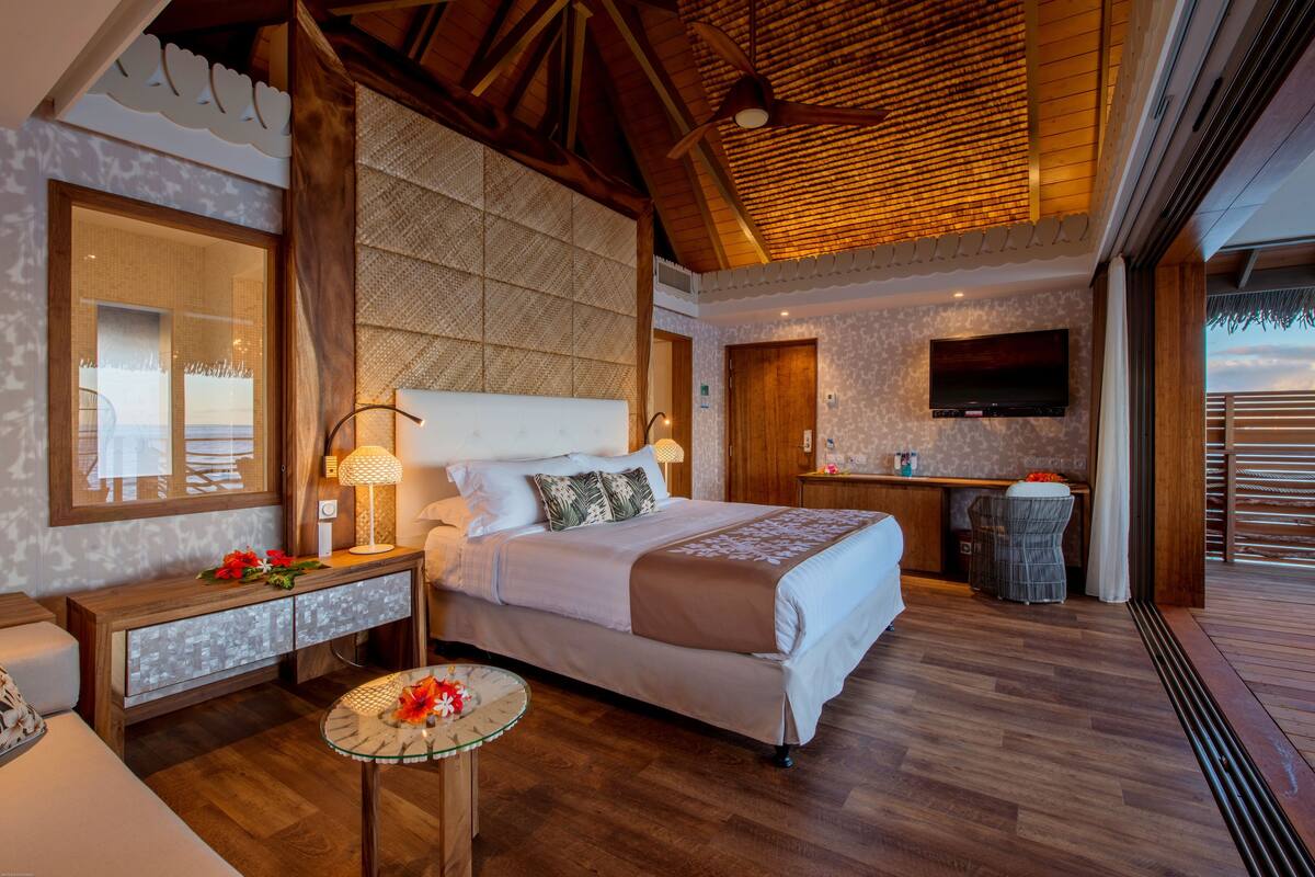A spacious bedroom with a large bed, a desk, and a TV.