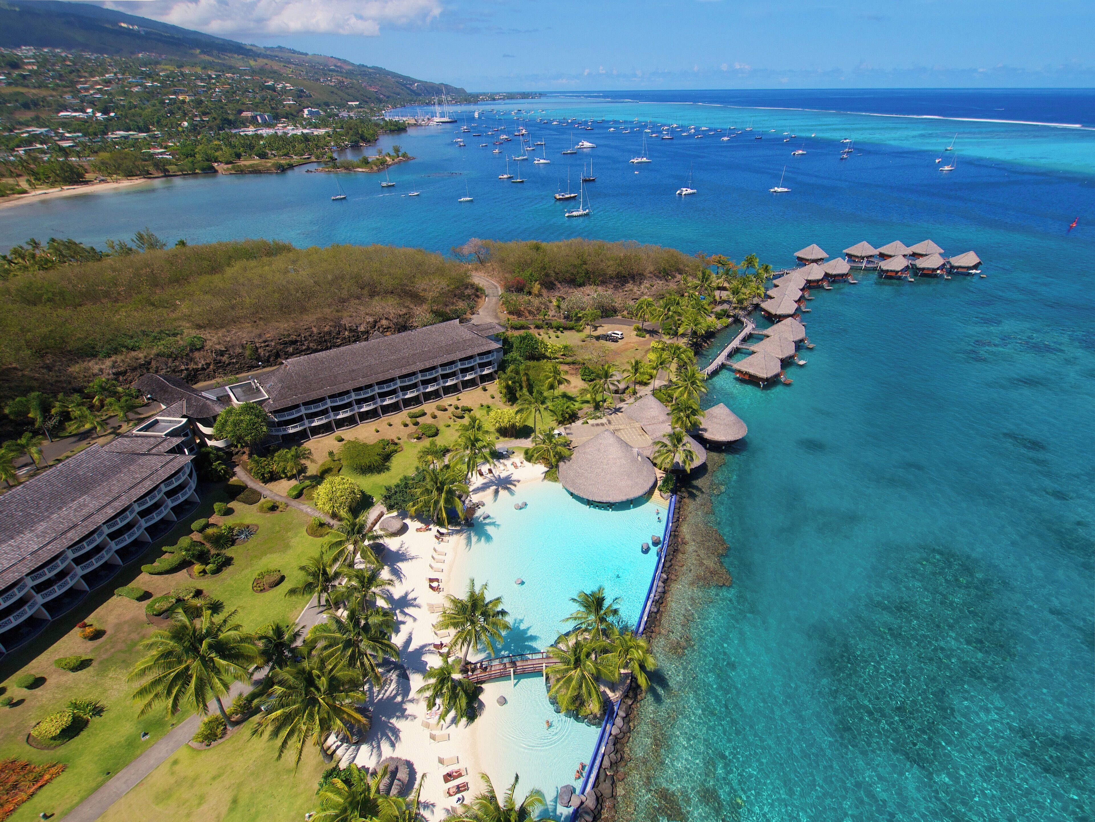 A resort with a pool, overwater bungalows, and a view of the ocean.