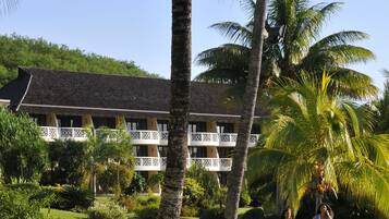 Un resort con una construcción tradicional, palmeras y un césped bien cuidado.