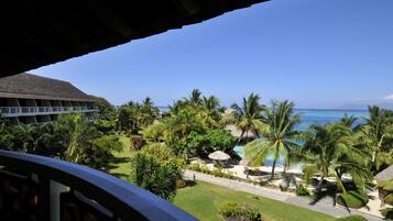 A resort with a pool area, palm trees, and a view of the ocean.