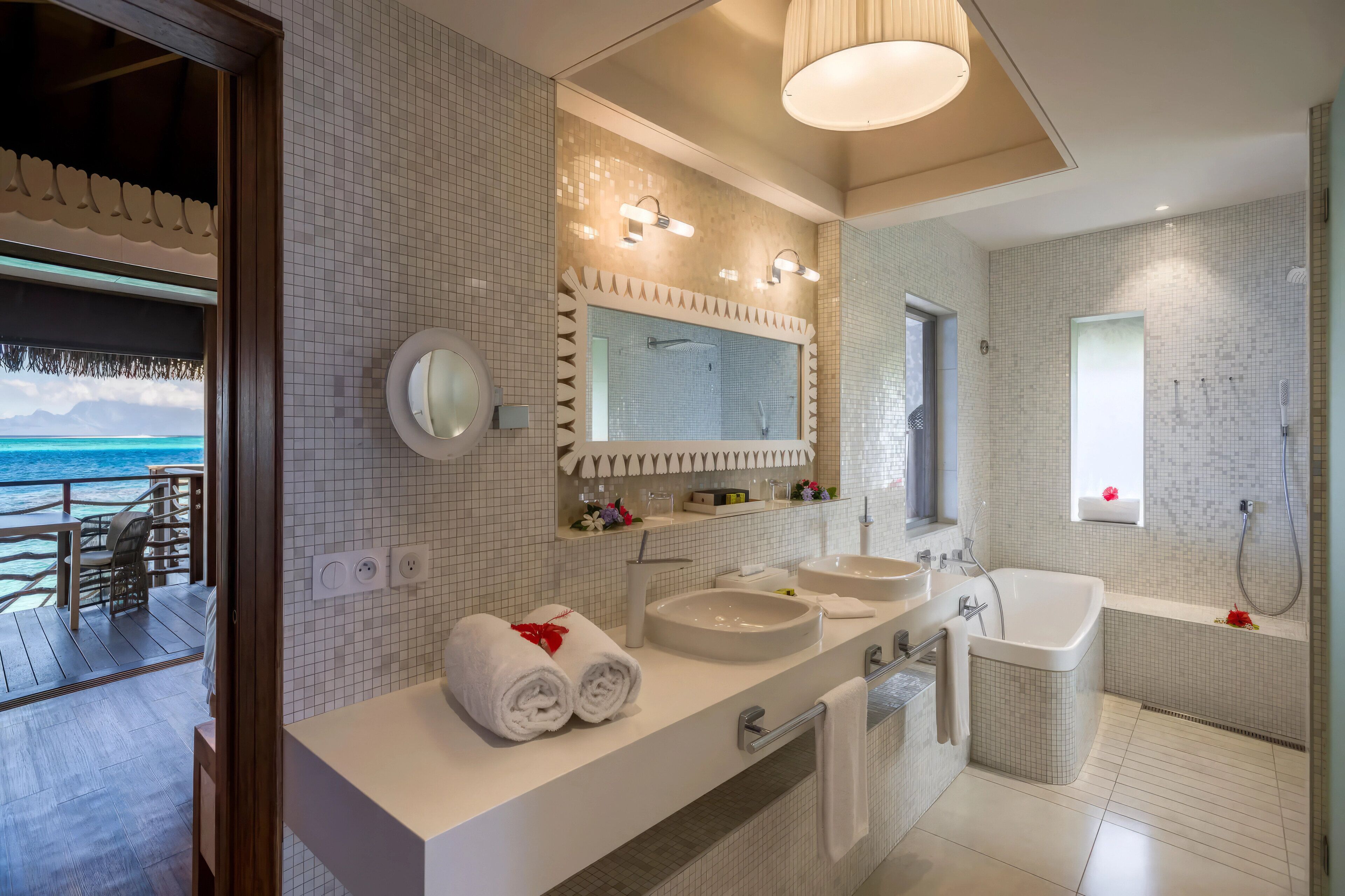 Un baño moderno con dos lavamanos, un espejo grande y una bañera.