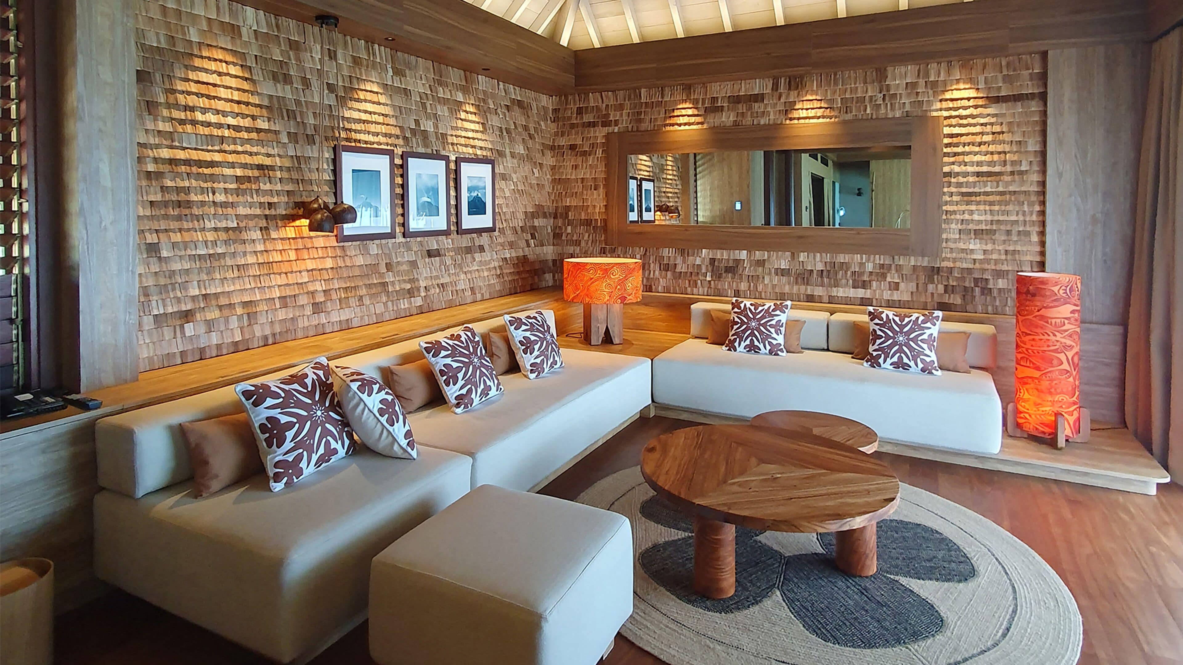 A modern living room with a sectional sofa, a wooden coffee table, and a large mirror.